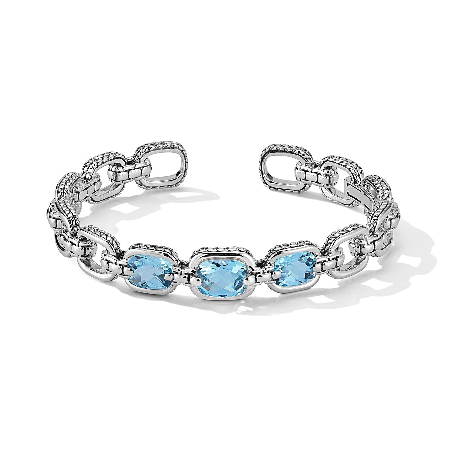 Our Sterling Silver Statement Link Hinged Cuff Bangle showcases three 10x8mm cushion Sky Blue Topaz gemstones. Each link is highlighted with Basketweave pattern and is bridged with Box Chain. Cuff ope